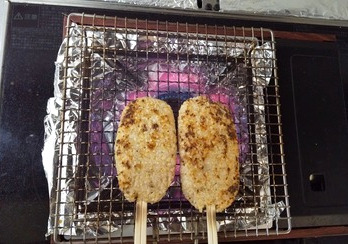 五平餅を動かしながら焼いている。