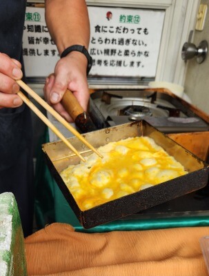 店主が玉子焼きフライパンで、だし巻きたまごを焼いている