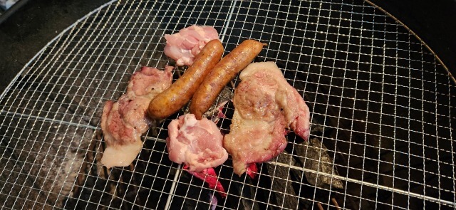 煙がモクモク上がり網の上で焼かれる野菜や肉