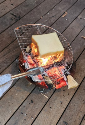 トングで焼網をもち、上にパンを置き火であぶっている