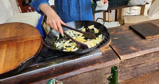 大きな鉄鍋で野菜をいためている